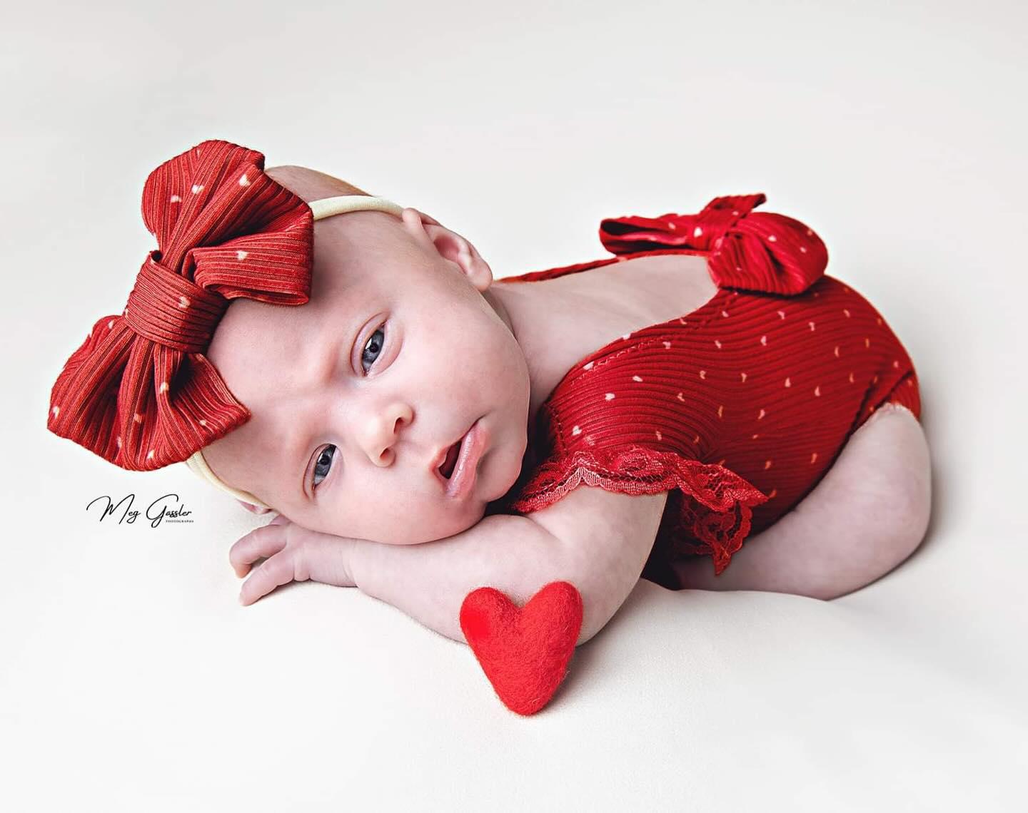 Las Vegs newborn photography with a baby girl in red with a heart on a photo studio backdrop